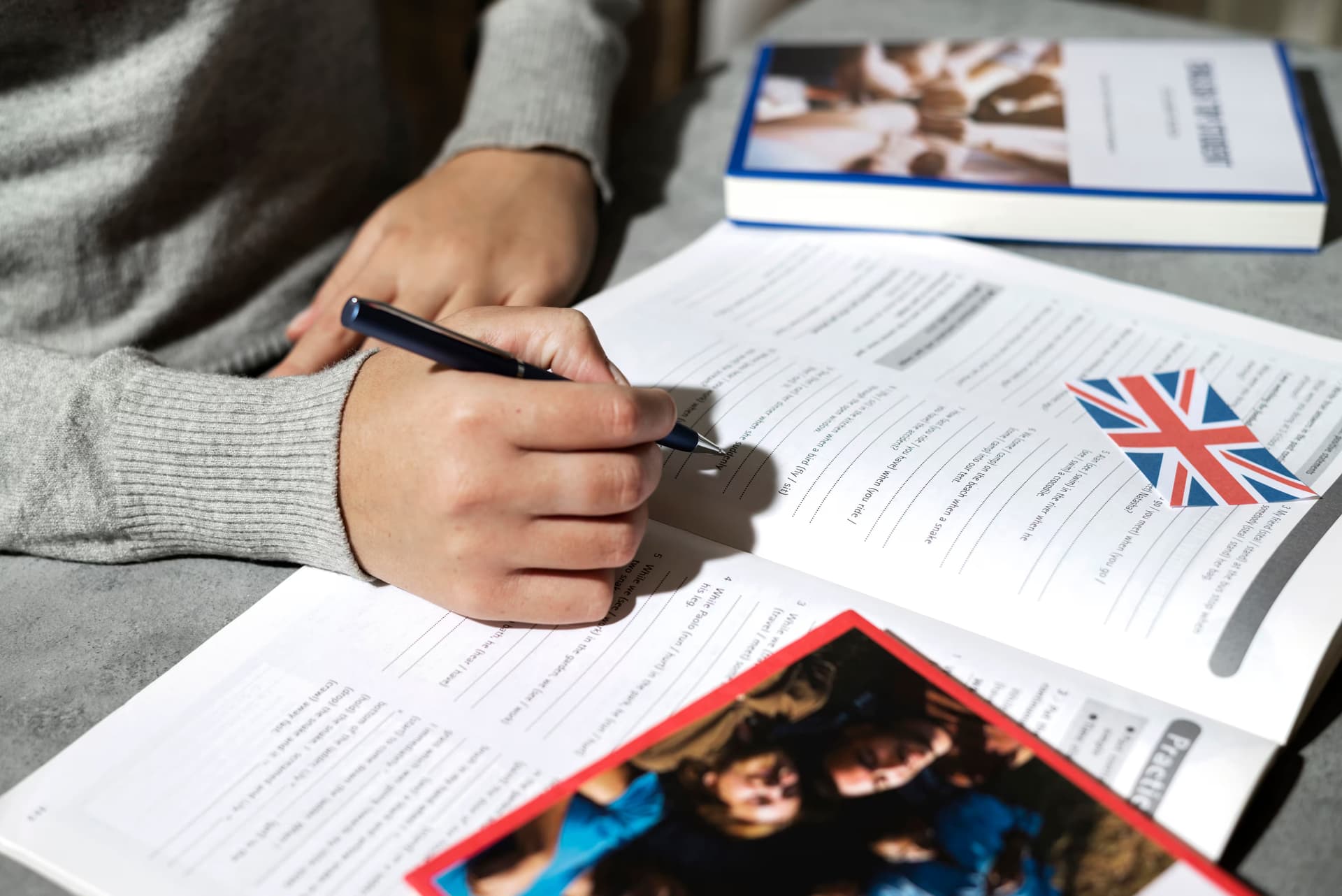 Foto de las manos de un alumno escribiendo en un libro de ejercicios de inglés